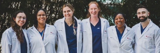 Group of smiling residents in white lab coats